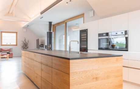 Eine weiße Wohnküche, offene Küche mit Kücheninsel aus Holz. komplett aus Eichenholz verarbeitet und produziert nach Maß von der Möbelwerkstatt HÄRING in der March Hugstetten in der Nähe von Freiburg